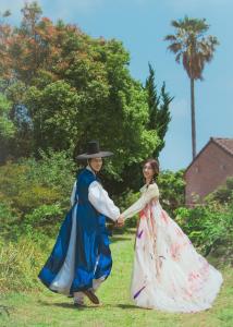a man and a woman in historical clothes are holding hands at Stay Aeok Jeju in Seogwipo