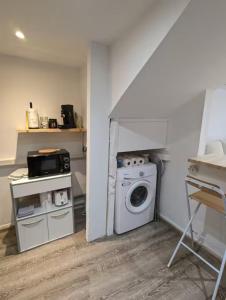 a laundry room with a washing machine and a microwave at Les nids de Lagasse in Agen
