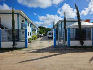 a building with a gate and a van parked on a street at Apto Garden Taperapuan 2 quartos com suíte in Porto Seguro