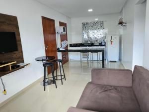 a living room with a couch and a kitchen at Apto Garden Taperapuan 2 quartos com suíte in Porto Seguro