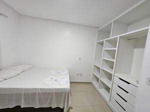a white bedroom with a bed and a closet at Apto Garden Taperapuan 2 quartos com suíte in Porto Seguro +4 photos