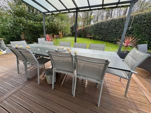 a dining table and chairs on a deck with an umbrella at Au Bois Dormant in Monterblanc