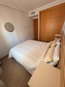 a bedroom with a white bed with a wooden door at Casa Sol Serena - Pool, Beach & Golf in Los Alcázares +19 photos