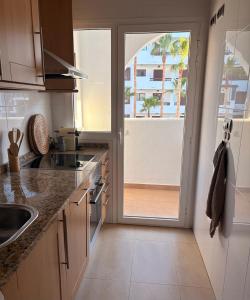 a kitchen with a sliding glass door to a balcony at Casa Sol Serena - Pool, Beach & Golf in Los Alcázares