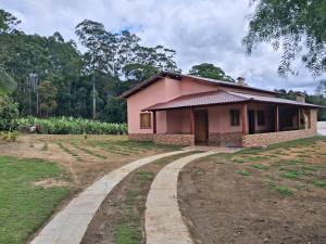 a small pink house with a dirt road at Cottage Saint Antoine in Pedra Azul
