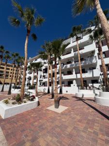 a group of palm trees in front of a building at Casa Sol Serena - Pool, Beach & Golf in Los Alcázares