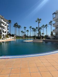 a large swimming pool with palm trees and buildings at Casa Sol Serena - Pool, Beach & Golf in Los Alcázares