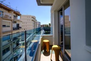 a balcony with two stools and a view of a city at FatCow Suites City Centre in Larnaca