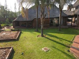 a yard with palm trees and a house at Villa Caramia Guest Lodge in Jan Kempdorp
