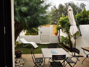 a patio with a table and chairs and an umbrella at "La Parenthèse balarucoise" in Balaruc-le-Vieux