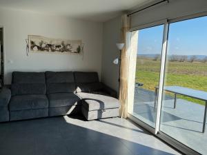 a living room with a couch and a sliding glass door at Maison de plain pied in Certines