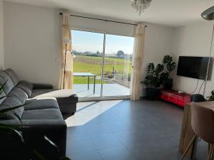 a living room with a couch and a sliding glass door at Maison de plain pied in Certines