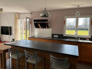 a kitchen with a large black counter and chairs at Maison de plain pied in Certines