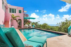 a swimming pool in front of a pink house at Villa Serena Water Island in Water Island