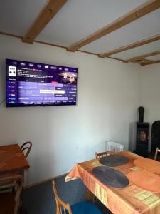 a television on the wall of a room with a table at Chata Anežka in Stará Ves