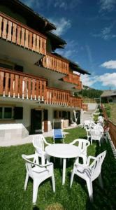 a patio with white chairs and a table and a building at Appartamenti Albert in Canazei