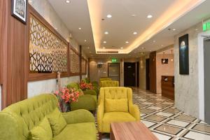 a waiting room with yellow chairs and a table at Salsbil Almasi Hotel in Medina