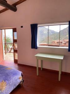 a bedroom with a table and a window with a view at Raíz Azul in Pisac