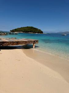 a wooden table sitting on a beach next to the ocean at Meta apartment in Ksamil