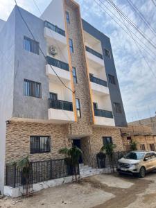 a building with a car parked in front of it at Residence Meuble Zac Mbao in Kammba
