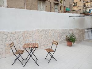 two chairs and a table in front of a stone wall at Terrazza Cristallini Napoli in Naples