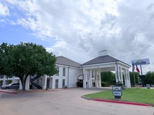 a white building with a sign in front of it at Days Inn by Wyndham Granbury in Granbury