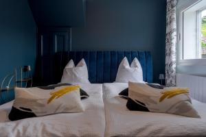a bed with white pillows and a blue wall at Chambres d'hôtes Les Vergers in Chalais