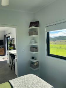 a bedroom with a window and a desk and a bed at Boutique Tiny House Stargazing & Rural Views in Parore