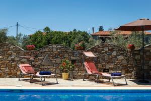 two chairs and an umbrella next to a pool at Seranides Boutique Hotel in Kato Gatzea