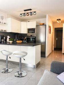 a kitchen with white cabinets and bar stools at Studio cosy, Centre Port, Piscine, proche plage in Cap d'Agde