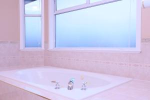 a white tub in a bathroom with a window at 7Bedroom Beautiful and spacious home in Surrey +9 photos