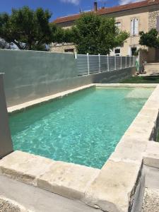 a swimming pool with blue water in front of a building at Maison Douce in Châteaurenard