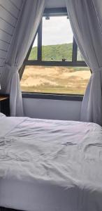 a white bed in a room with a window at Dunas beach club in Jaguaruna +9 photos
