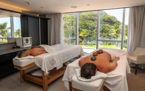 two people laying in beds in a room at Suíte Luxo Mar em Hotel Nacional in Rio de Janeiro