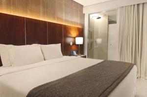 a bedroom with a large white bed and a shower at Suíte Luxo Mar em Hotel Nacional in Rio de Janeiro