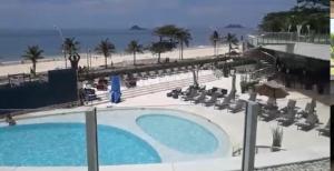 a view of the pool and beach from the balcony of a resort at Suíte Luxo Mar em Hotel Nacional in Rio de Janeiro