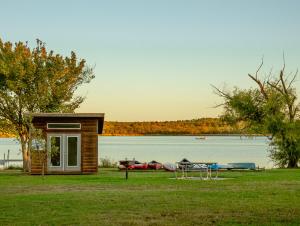 a small cabin next to a lake with a table and boats at Premium Lakefront Cabin 1 The Armadillo in Bastrop