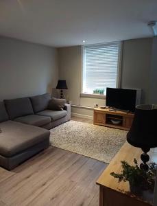 a living room with a couch and a flat screen tv at The Mews Holywell in Holywell