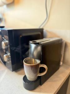 a coffee cup on a stand next to a microwave at Studio with Private Spa Garden in Njarðvík