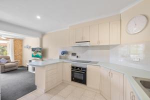 a kitchen with white cabinets and a clock on the wall at Ocean Shores Apartment 2 in South West Rocks