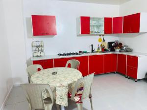 a kitchen with red cabinets and a table and chairs at Maison yassine in Douz