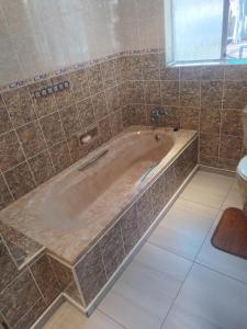 a bath tub in a tiled bathroom with a toilet at J&J Paradise Guesthouse in Pietermaritzburg