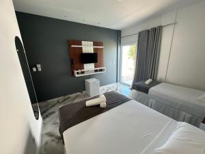 a hotel room with two beds and a television at Pousada WL Império in Canoa Quebrada +136 photos
