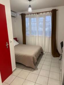 a bedroom with a bed and a large window at Le Petit QG in Schœlcher