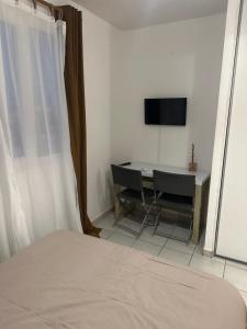 a bedroom with a bed and a table and a television at Le Petit QG in Schœlcher