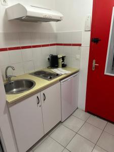 a small kitchen with a sink and a red door at Le Petit QG in Schœlcher