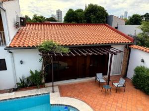 a house with a tile roof and a swimming pool at Casa KOMU in Asunción