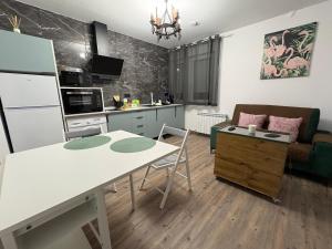 a kitchen and living room with a white table and chairs at Sueña Toledo- Apartamentos turisticos con piscina in Toledo