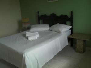 a bedroom with a bed with white sheets and pillows at Pousada Dom Diego in Jacaraípe