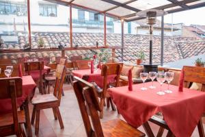 a restaurant with red tables and chairs with wine glasses at Hotel Calle Angosta in Cuenca